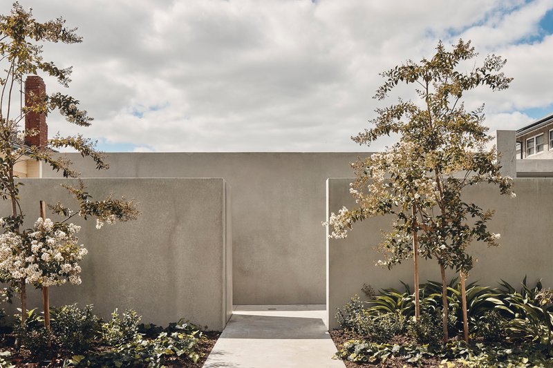 Pedestrian gateway cut through the concrete wall with flowering trees framing the passage