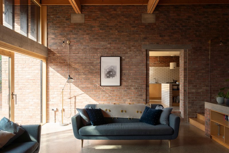Living space with exposed brick wall and timber roof beams under diffused afternoon sunlight