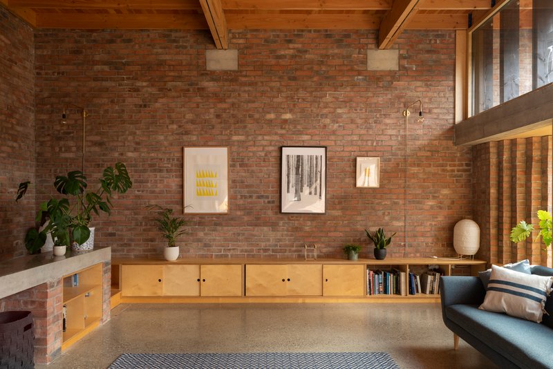 Plywood storage wall with open shelving beneath exposed rafters and mezzanine level above