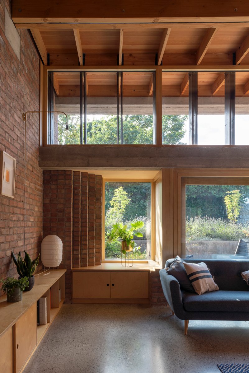 Built-in window seat framed by plywood panels with steel columns and timber joists overhead