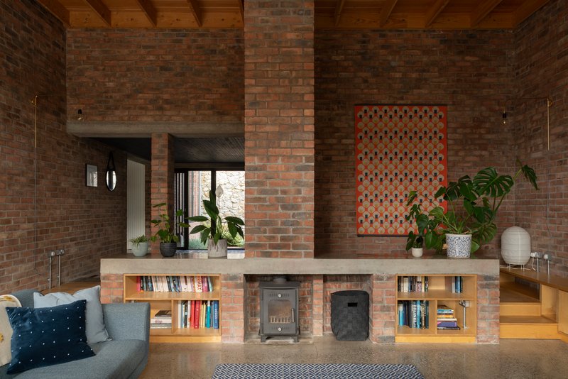 Brick fireplace with built-in bookshelves and exposed timber ceiling beams above a low seating area