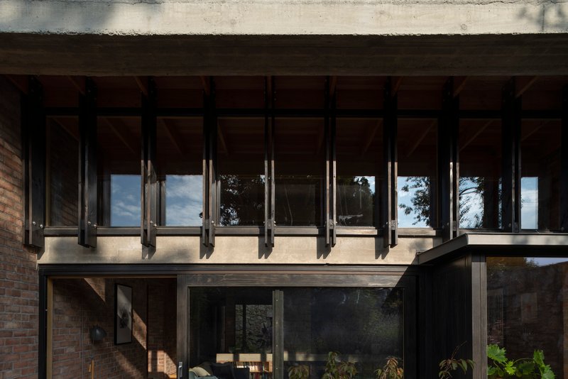 Cantilevered upper floor with exposed steel beams and concrete soffit overhanging glazed lower level