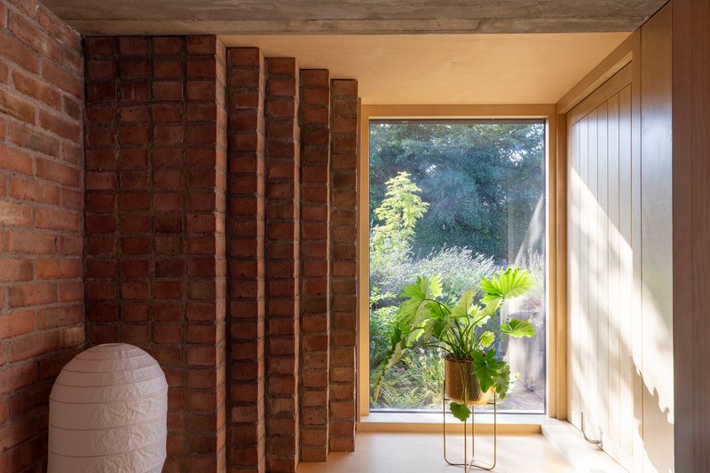 Corner niche with exposed timber joists and brick wall adjacent to picture window overlooking garden