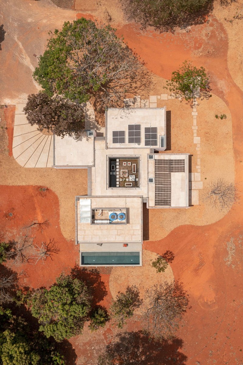 Aerial drone view of white flat-roofed volumes with pool and courtyard on red earth terrain