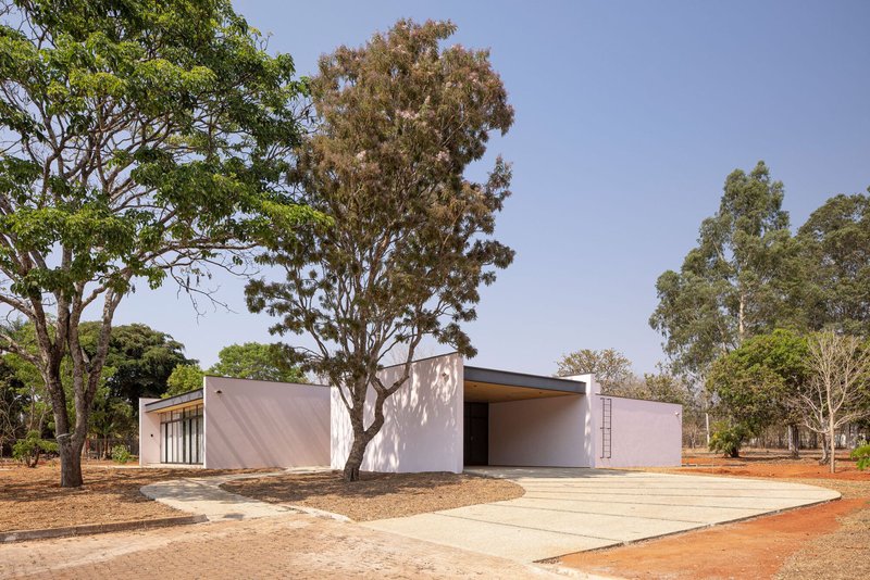 White rendered volumes with flat roof surrounded by eucalyptus trees and red gravel courtyard