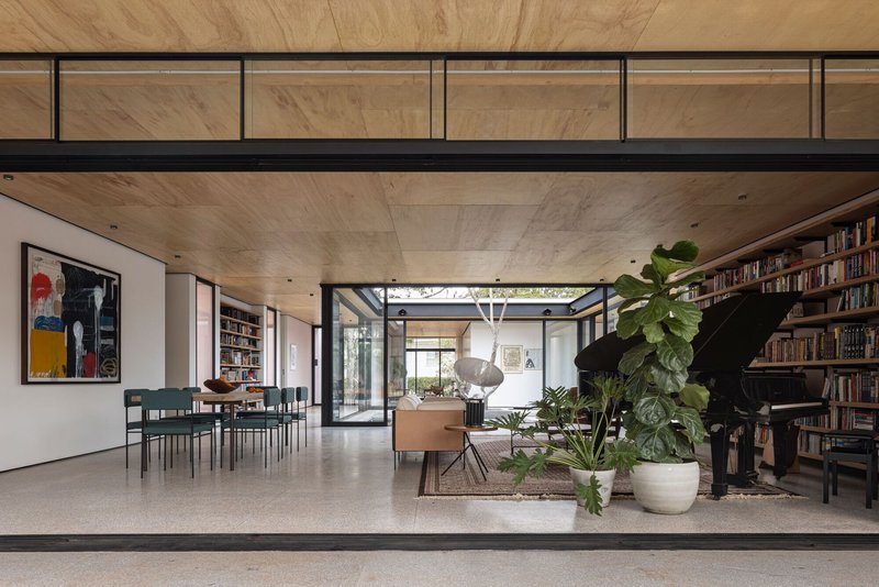 Open-plan living space with timber-clad ceiling and clerestory glazing overlooking the planted courtyard
