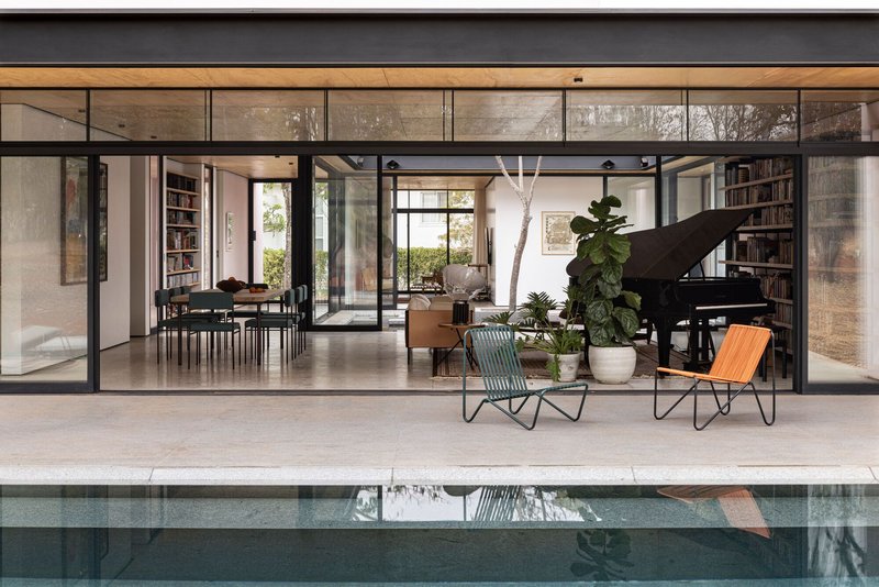 Fully open steel-framed glazed wall revealing the interior living space and reflecting pool beyond