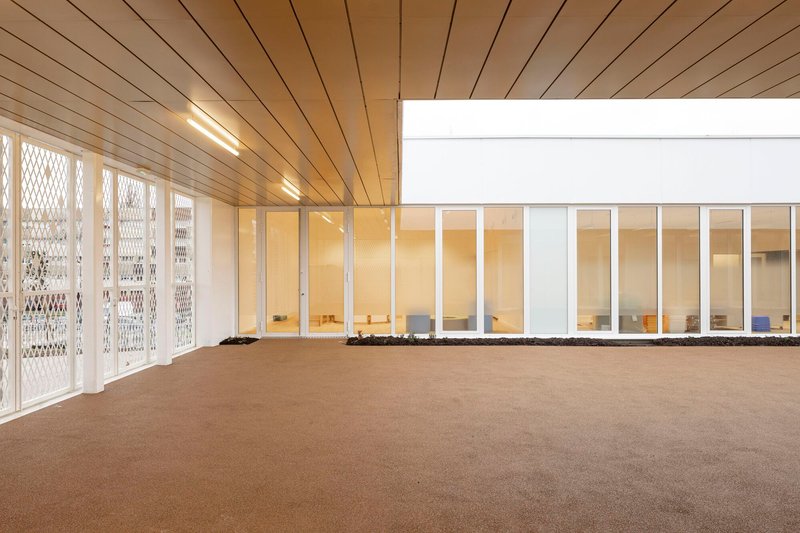 Interior room with timber plank ceiling and perforated metal doors opening to a glazed corridor