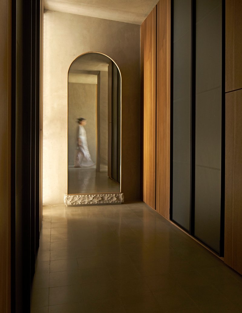 Corridor with arched opening, timber paneling and a figure passing through in motion blur