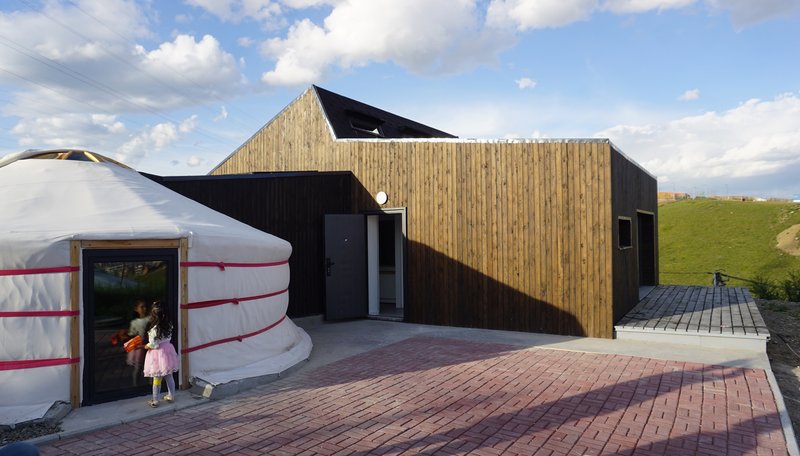 Entry courtyard with brick paving connecting the yurt and the vertical timber-clad volume