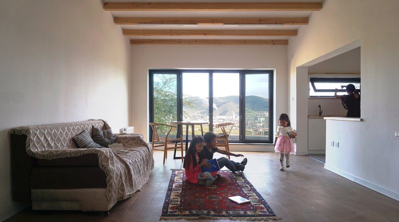 Living room with exposed timber ceiling beams and glazed doors opening to a distant mountain view