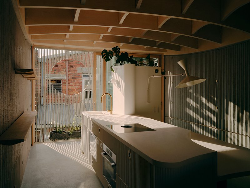 Kitchen with white stone island and vertical slat screen filtering afternoon sunlight from the courtyard