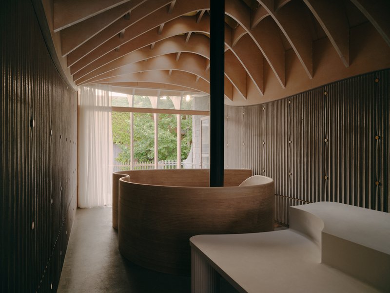 Interior reception area with curving timber desk beneath a ribbed timber ceiling and vertical slat walls