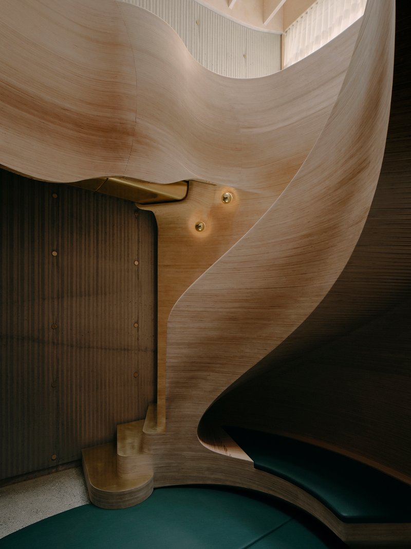 Detail of brass handrail anchoring into laminated timber wall next to vertical slat partition