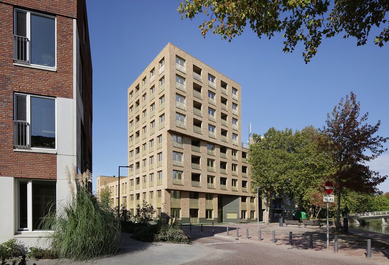 Street view of the gridded brick tower with a cantilevered mid-section under a clear blue sky