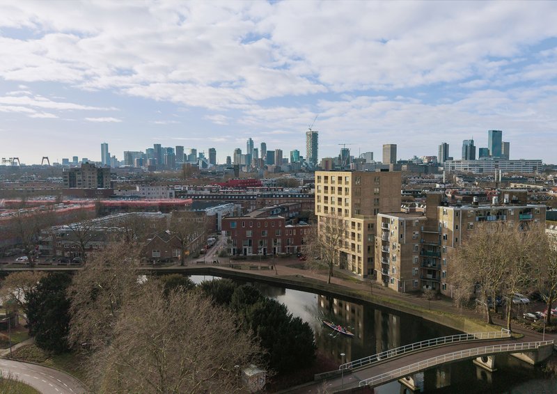 Elevated view of the residential tower beside a canal with the city skyline in the distance