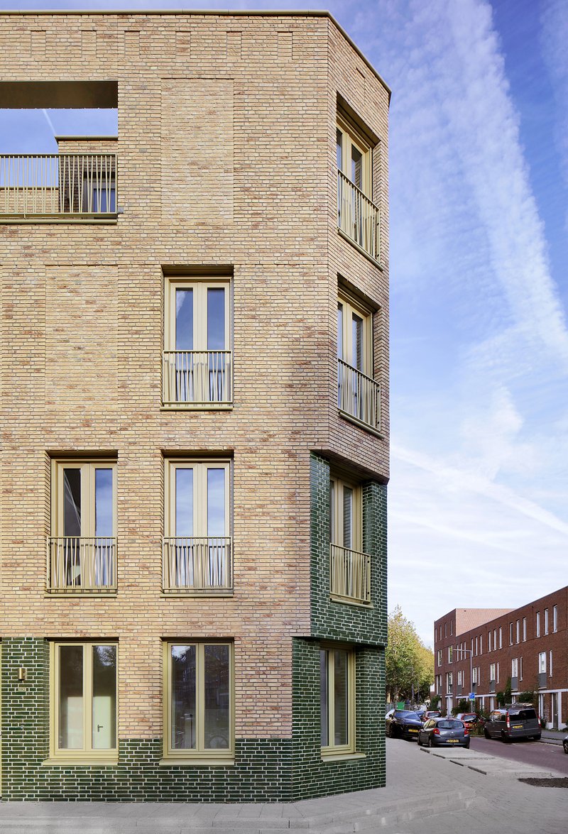 Corner detail showing the alternating buff and green brick cladding under a partly cloudy sky