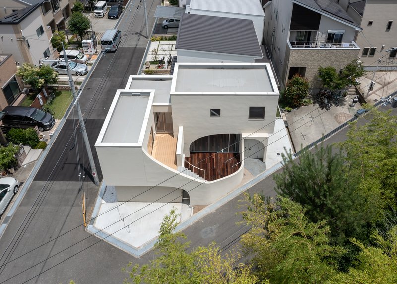 Aerial view of white roof terraces with a curved timber deck nestled among neighboring houses