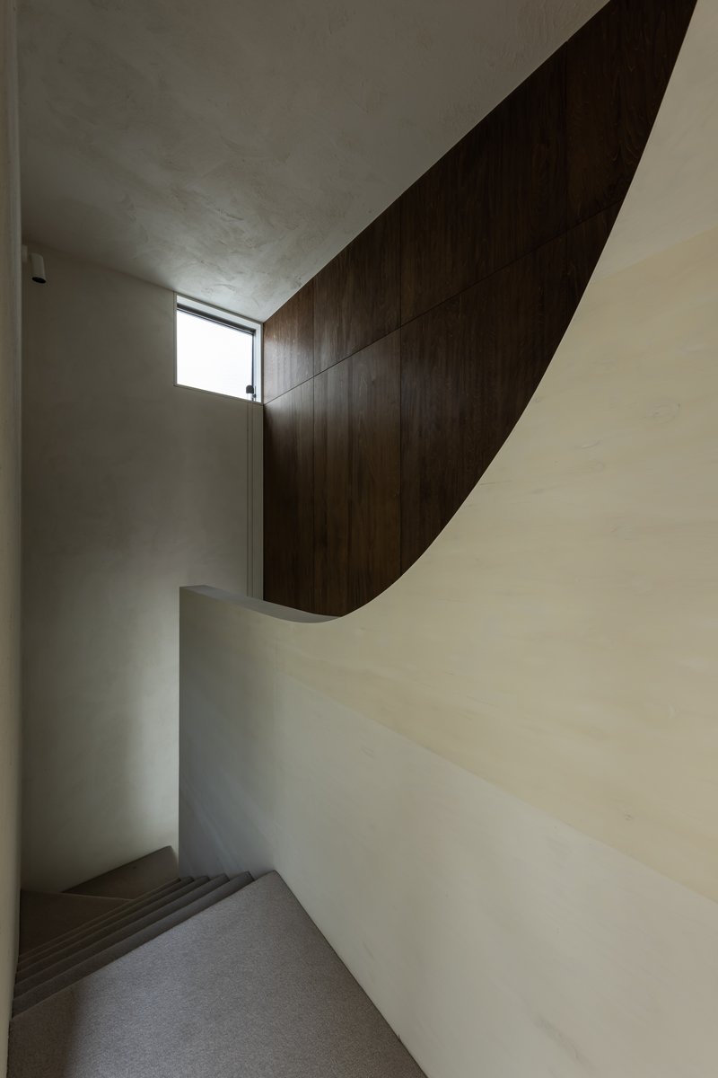Staircase with sweeping dark wood panel wrapping the upper wall beneath a vaulted plaster ceiling