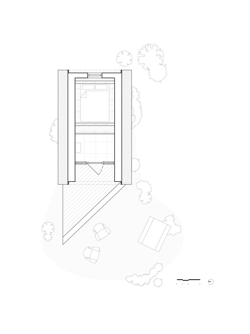Floor plan showing two-story rectangular volume with diagonal outdoor deck and scattered site furniture among trees