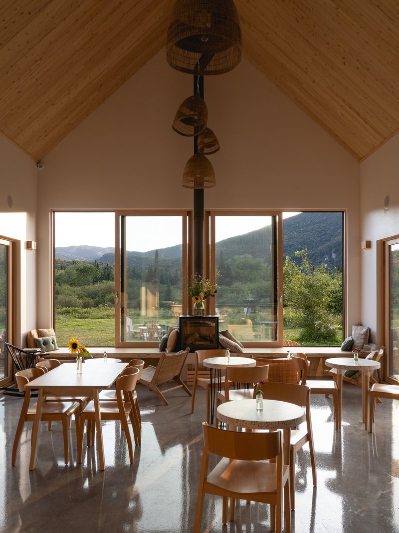 Dining hall interior with vaulted ceiling, timber-framed windows framing mountain views and woven pendant lights