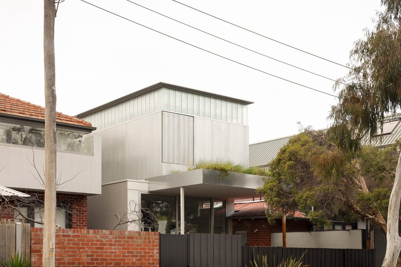 Street view of the two-storey addition with vertical metal cladding above a cantilevered terrace and dark fence