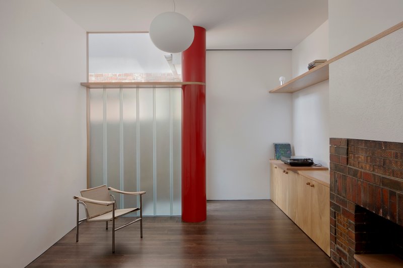 Living room with red cylindrical column, translucent sliding screen and low cabinet beside brick fireplace