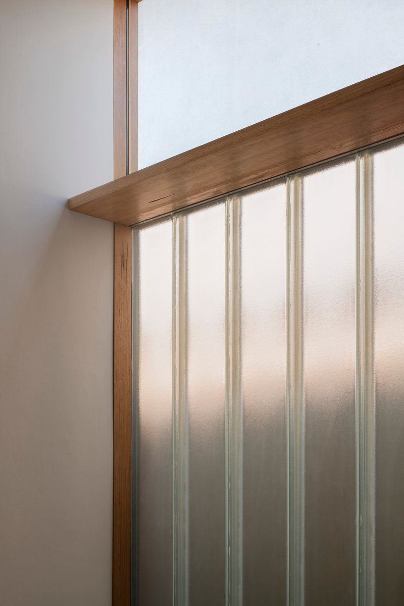 Close-up of timber handrail meeting translucent polycarbonate wall panel with vertical supports