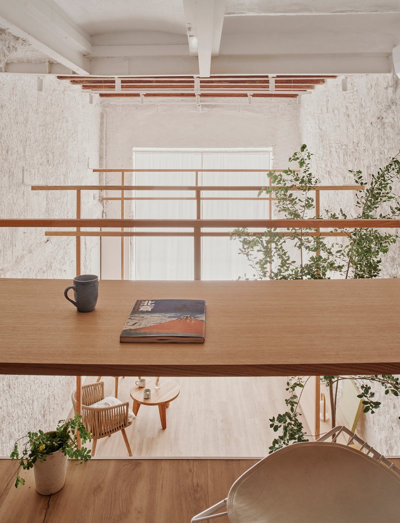 View from mezzanine workspace showing timber desk with mug and book overlooking the lower seating area