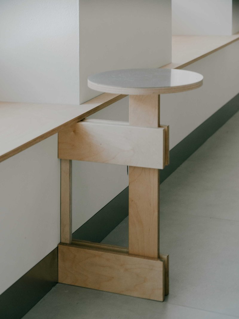 Light wood staircase with rounded handrail platform casting shadows on white walls in soft daylight