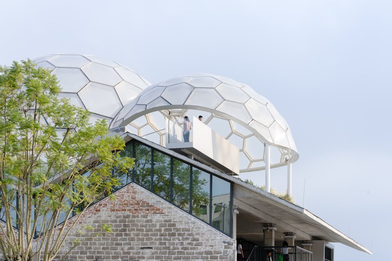 Hexagonal dome structure rising above a brick base with visitors on the upper deck and bamboo trees
