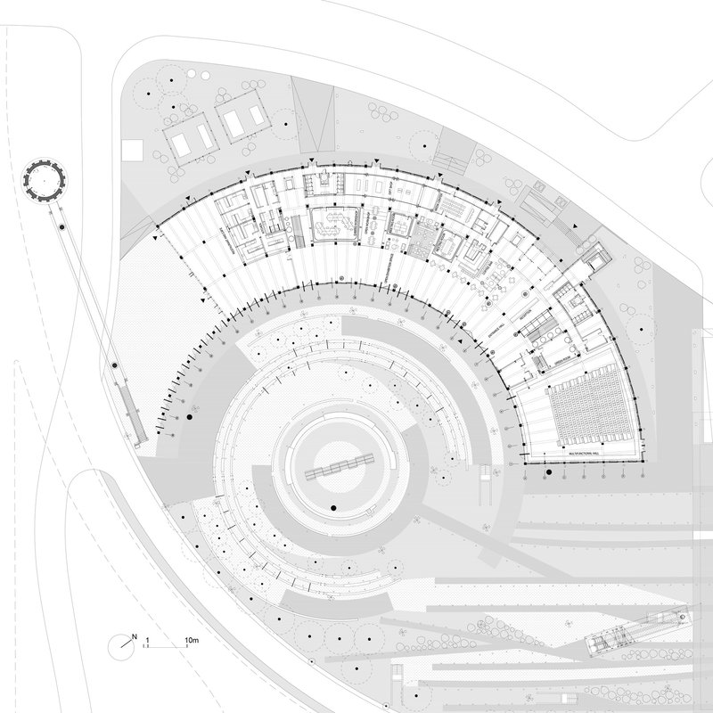 Site plan drawing showing a crescent-shaped building wrapping around a circular central courtyard with adjacent parking areas