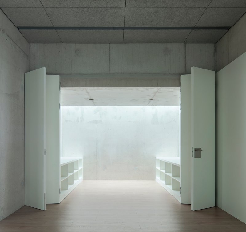 Concrete room with white double doors opening to a bright space with built-in shelving