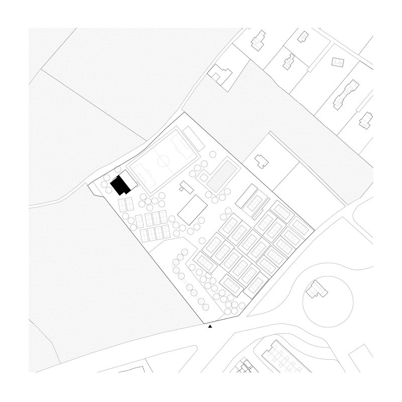Site plan drawing showing a rectangular building within a tree-lined plot surrounded by roads