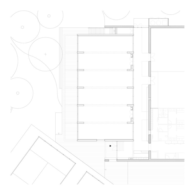 Ground floor plan drawing showing open interior spaces with staircases and tree canopies outside