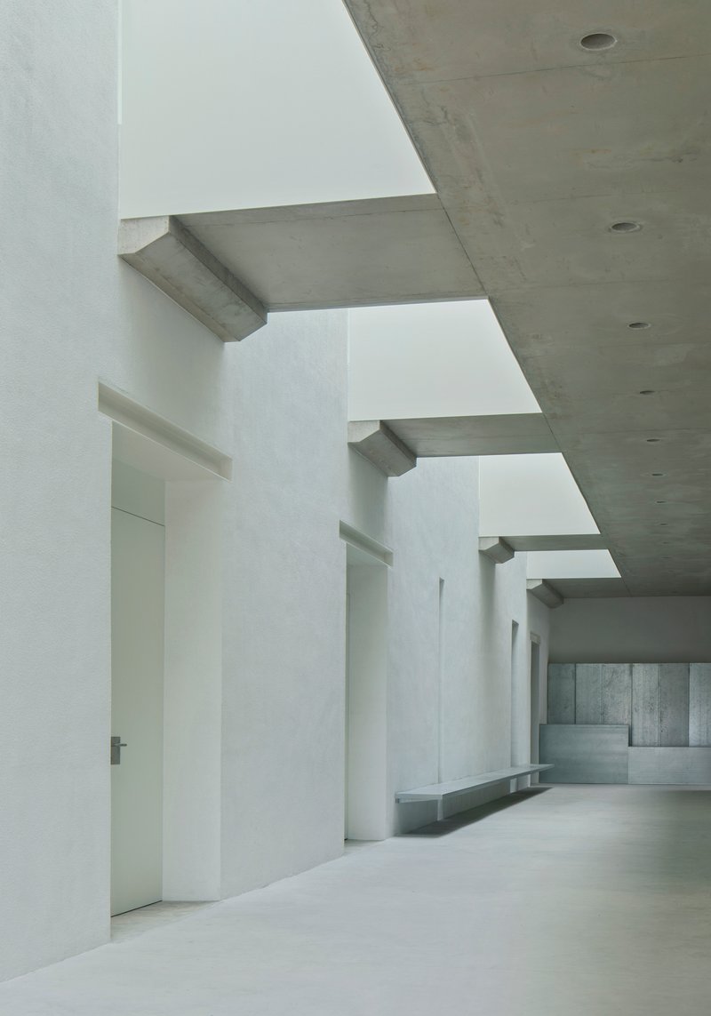 Interior hall with white columns supporting concrete beams beneath square ceiling openings
