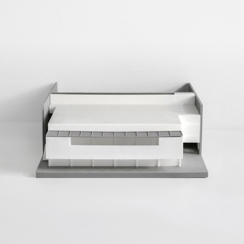 Physical scale model showing a flat-roofed volume with ribbon glazing and a cantilevered upper floor