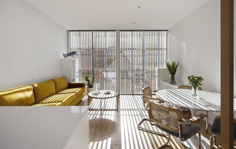Living room with vertical timber screen casting striped shadows across the floor and furniture