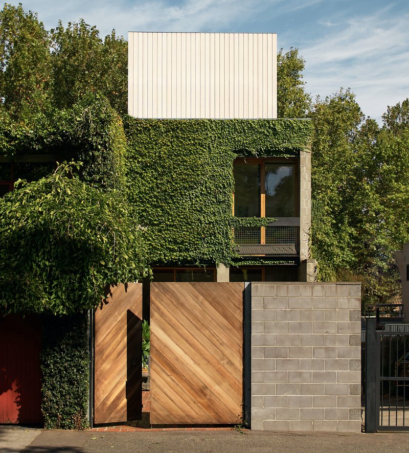 Street view of the diagonal timber garage doors and vertical metal cladding above an ivy-covered facade