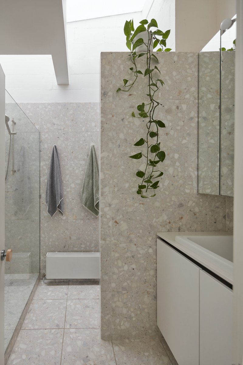 Bathroom with terrazzo tiles and hanging vine plant catching bright skylight from above