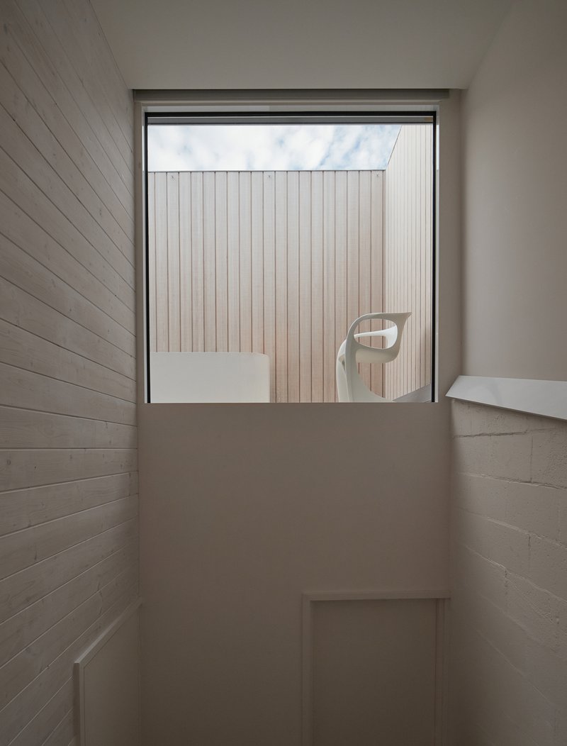 Window framing view of vertical timber cladding with chair reflection in glass
