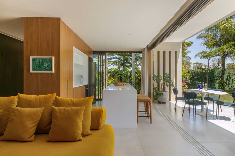 Interior opening to covered terrace with vertical slat screens and pool visible beyond palm trees