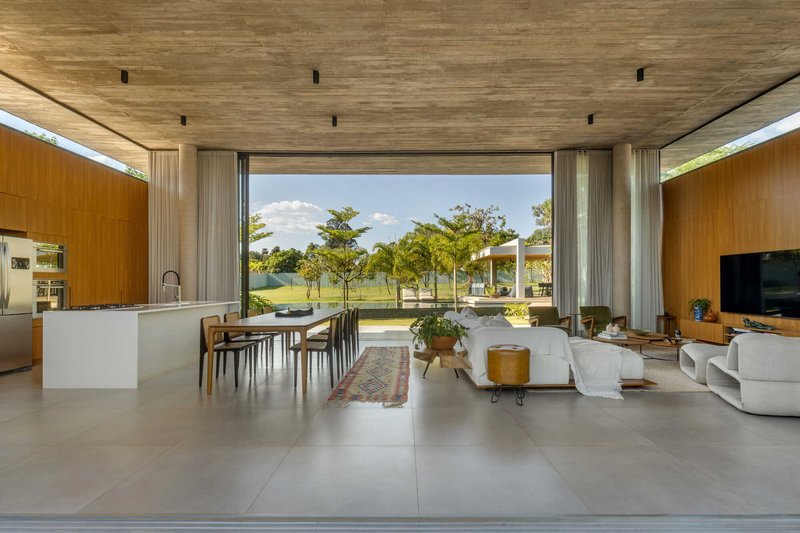 Open plan living space with timber ceiling and wood-paneled walls framing a view to lawn and trees