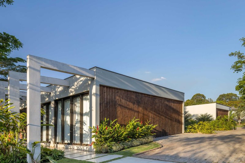 Street facade with vertical timber cladding and concrete frame beside planted beds in afternoon sunlight