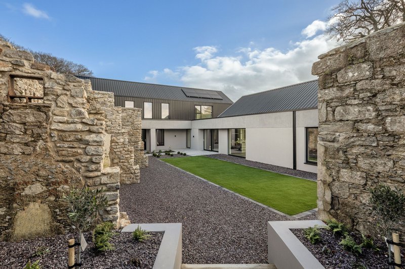 Courtyard framed by preserved stone ruin walls with gravel ground and planted beds