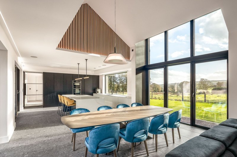 Open-plan dining and kitchen with timber slat ceiling panel and pastoral views beyond