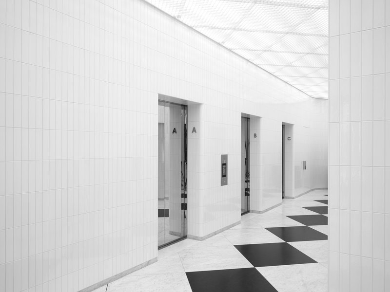 Elevator lobby with white tiled walls and black and white diagonal patterned floor