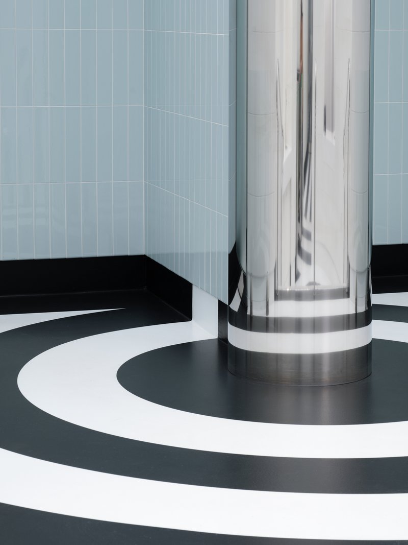 Polished metal column base meeting concentric black and white circular floor pattern