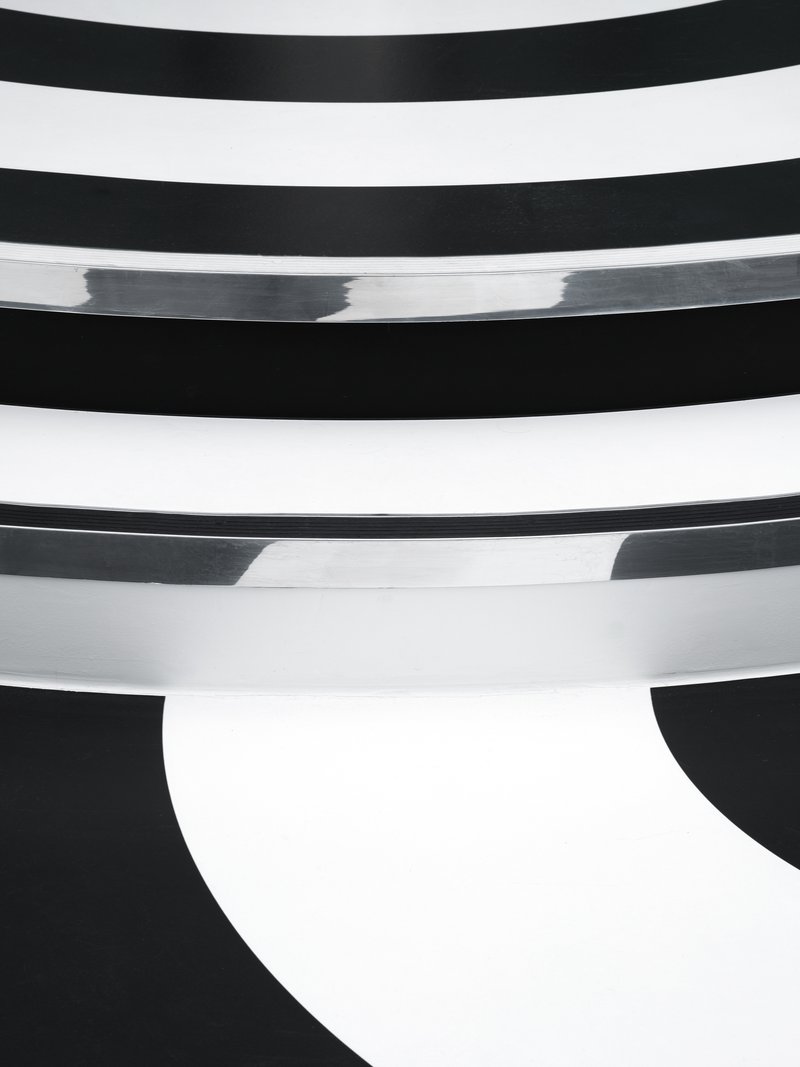 Close-up of curved white plaster balconies stepping down in horizontal bands against dark shadow