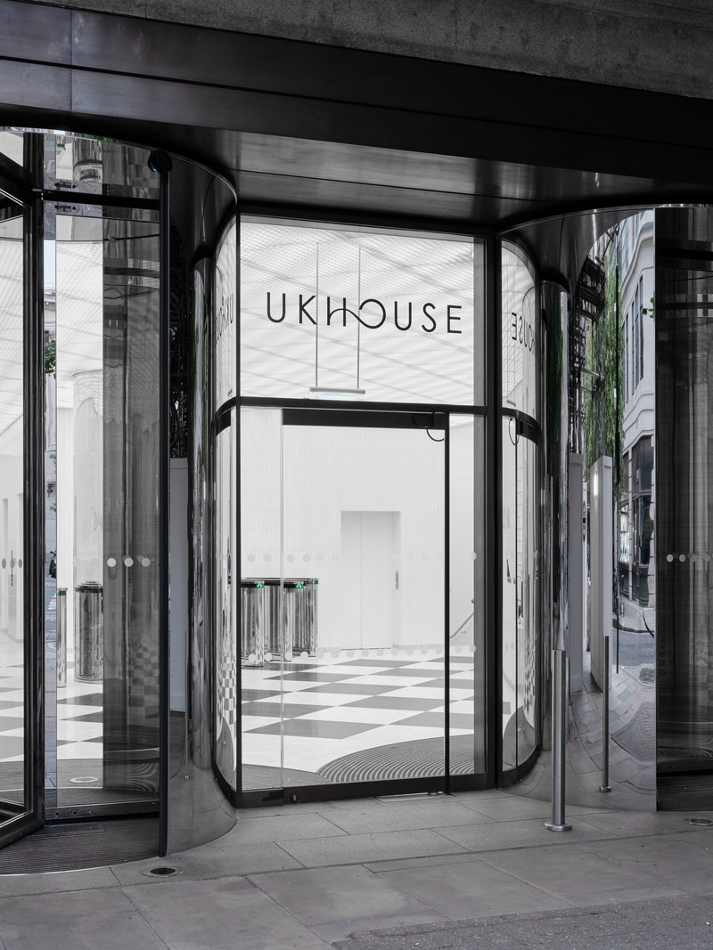 Close-up of the revolving door vestibule with curved chrome panels and view into the chequered lobby